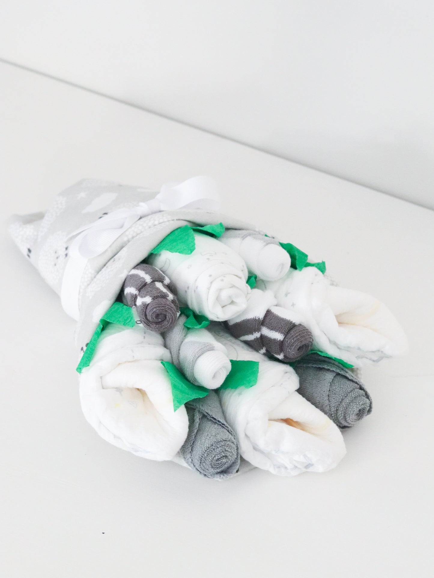 Stack of folded baby clothes on a white surface