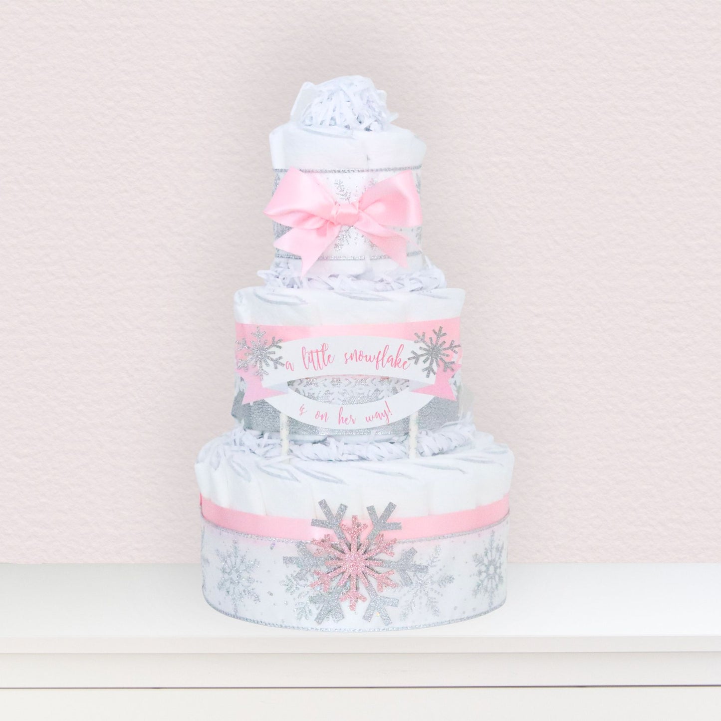 pink snowflake diaper cake on table