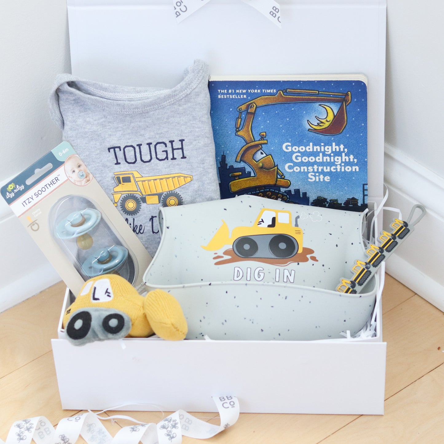 Baby gift set with construction-themed items including a shirt, book, and plush toy.