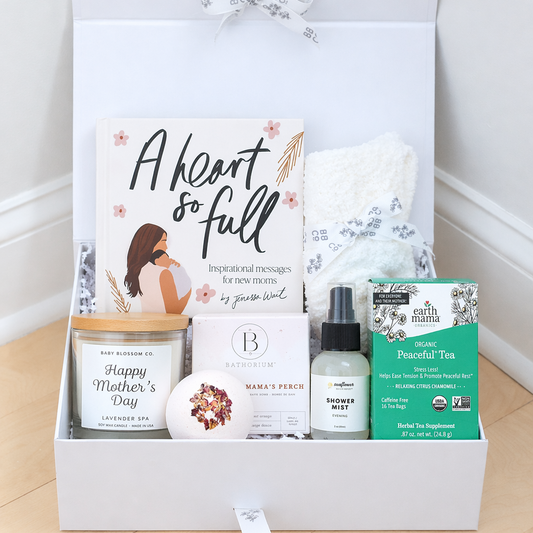 Mother's Day Gift box with various items including a book, candle, and tea box on a wooden surface.
