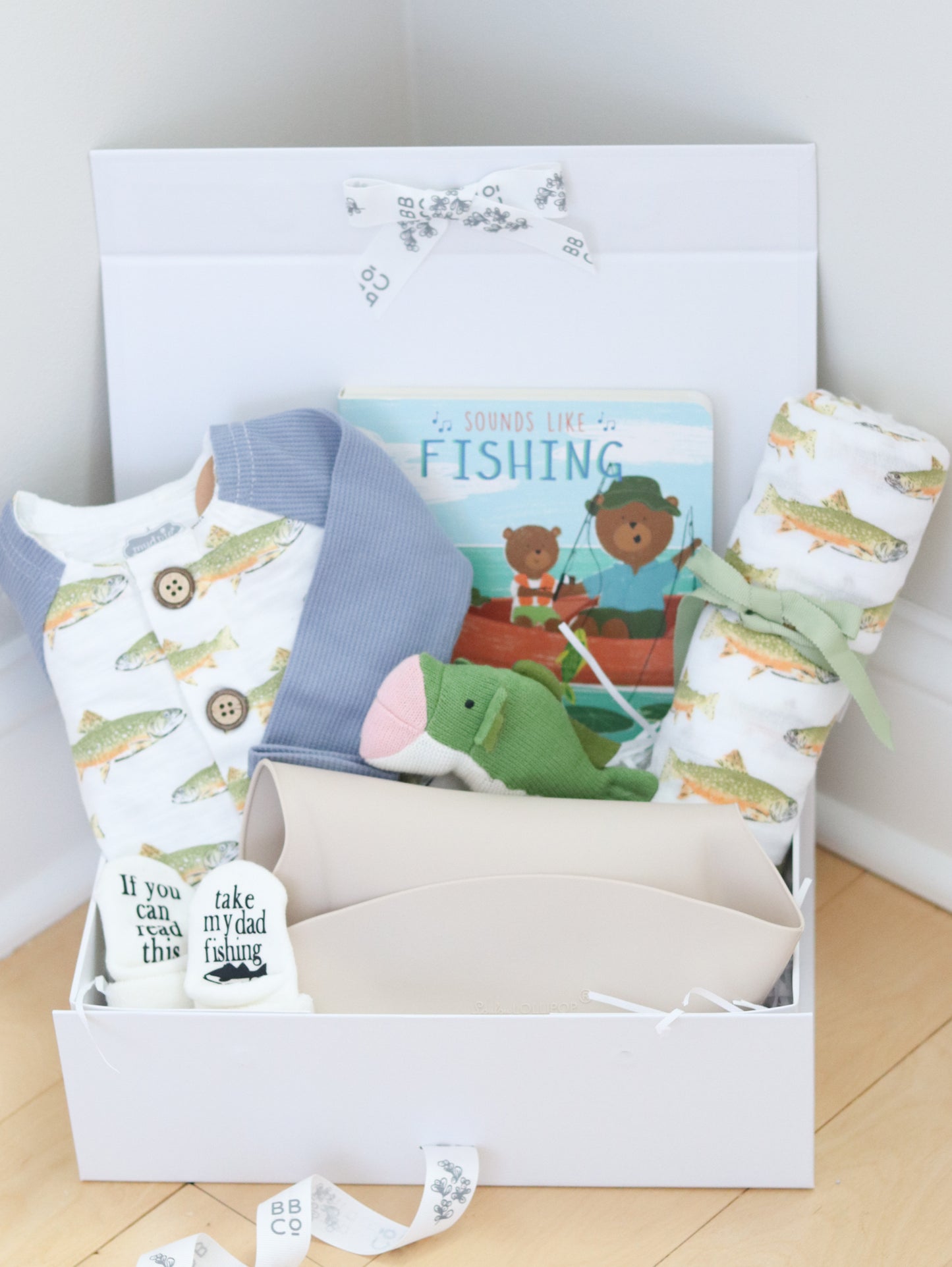 Gift set with fishing baby items including a book, socks, and a blanket in a box.