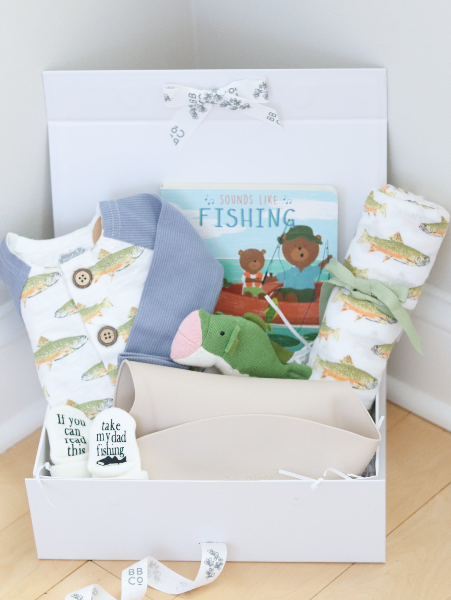 Gift set with fishing baby items including a book, socks, and a blanket in a box.